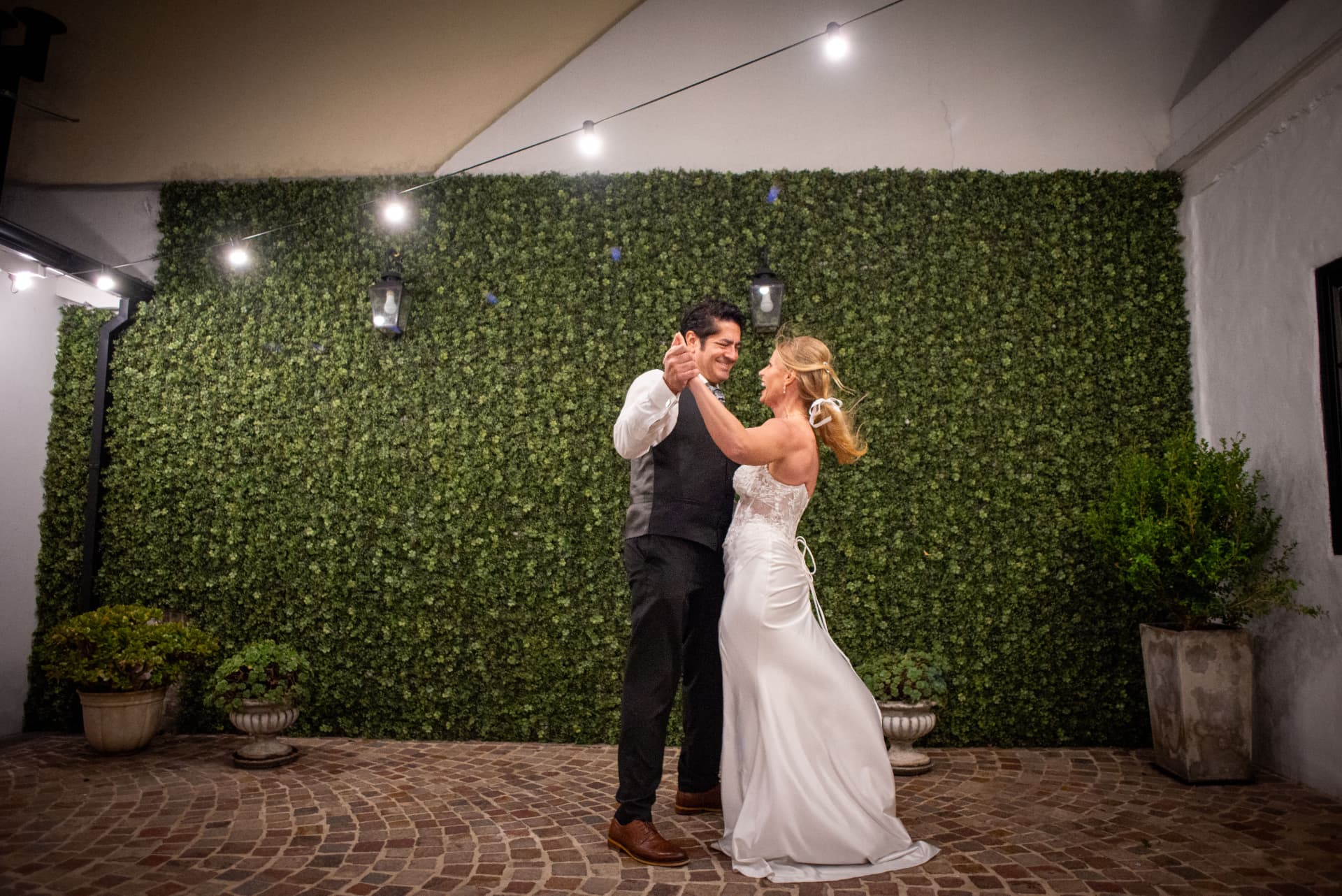 Primer baile de los novios frente al muro verde del patio