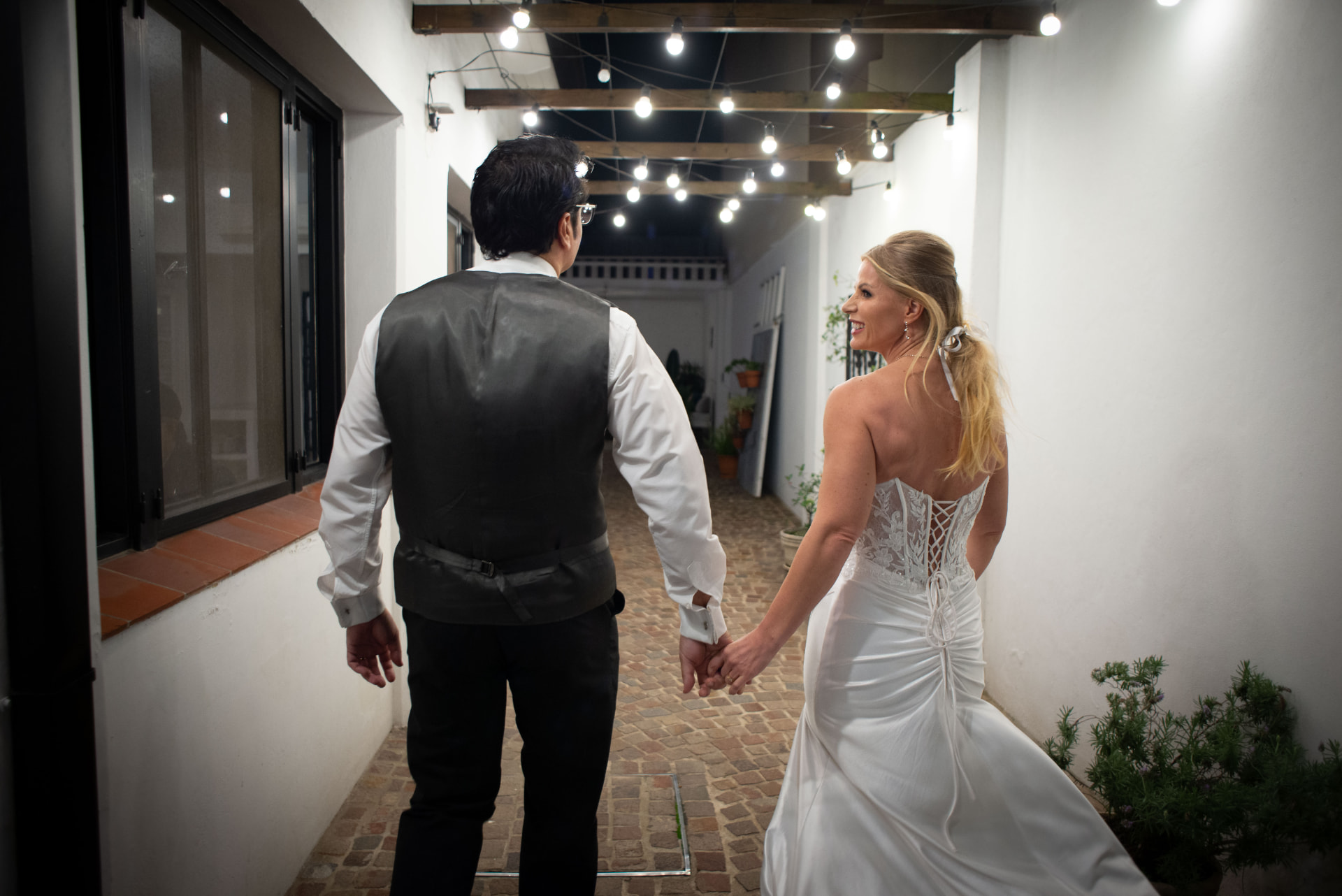 Novios caminando de la mano por el pasillo iluminado