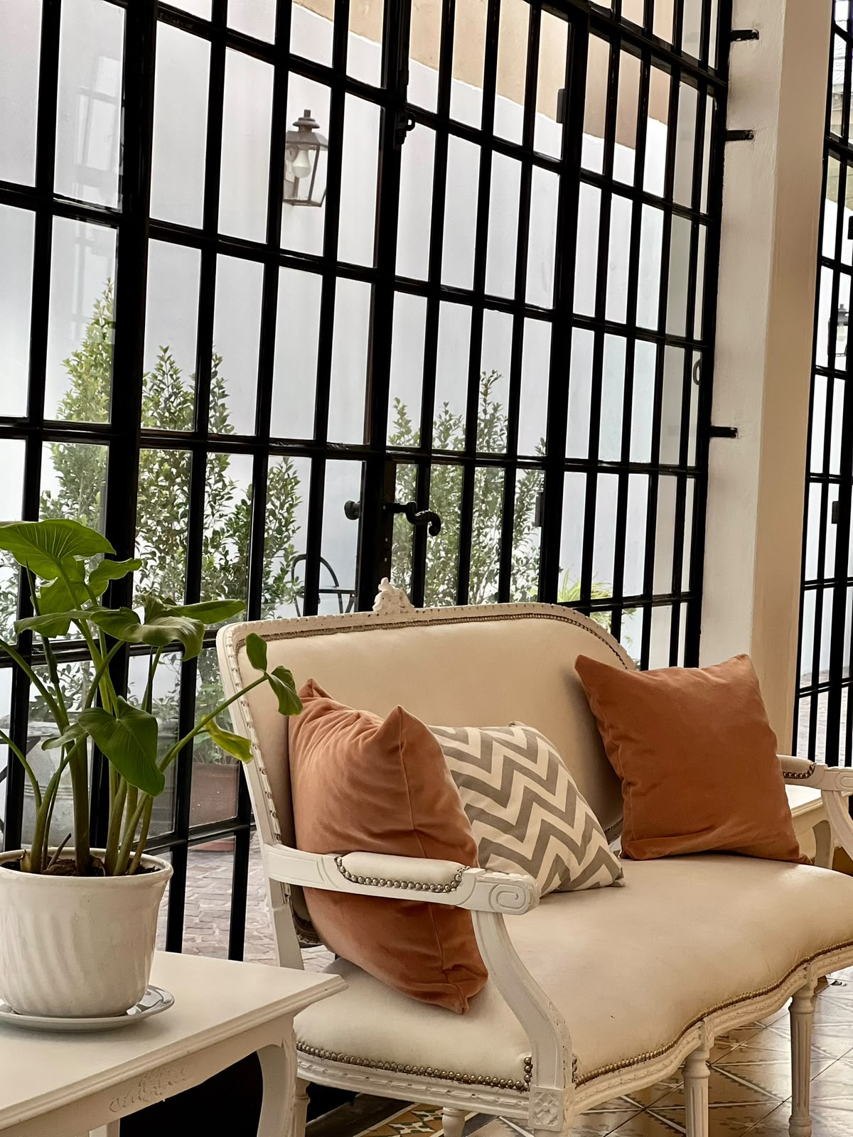 Rincón de la galería con sillón antiguo y ventanal de hierro