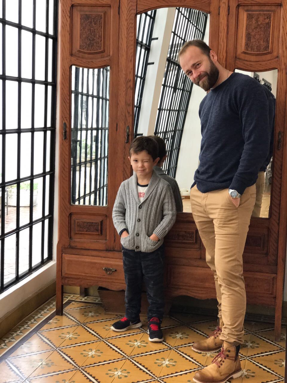 Padre e hijo junto a las puertas de madera y vitrales de la casa