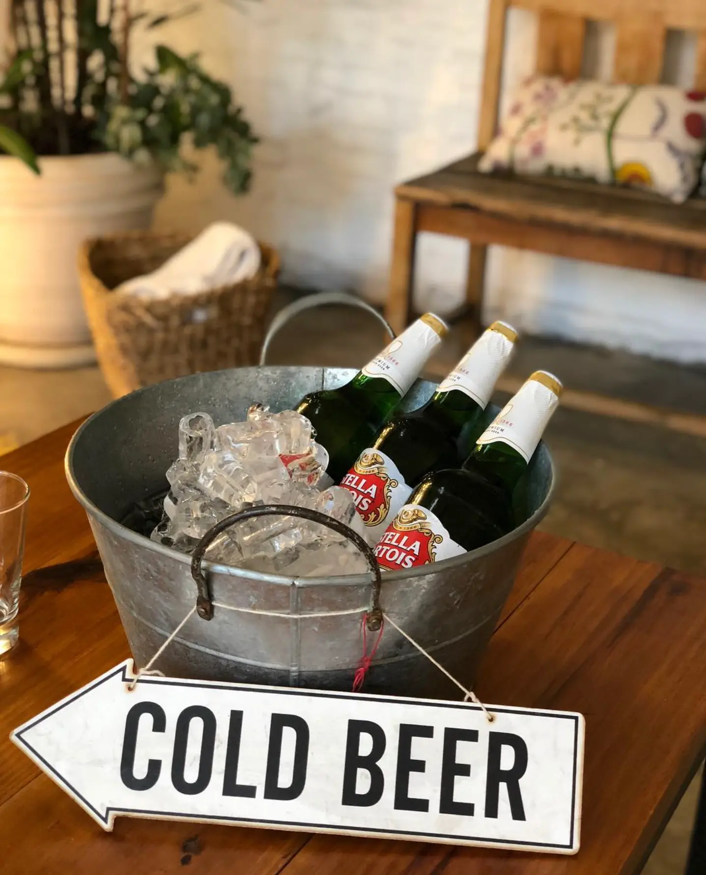 Fuentón con cervezas en hielo y cartel Cold Beer sobre mesa de madera