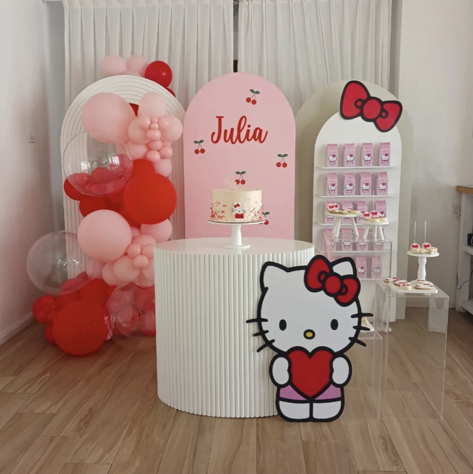 Ambientación infantil temática con globos rosas y rojos y mesa de dulces