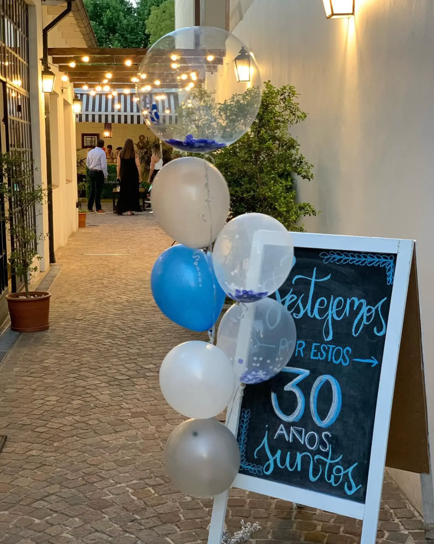 Globos y pizarra de bienvenida en la entrada del salón al atardecer